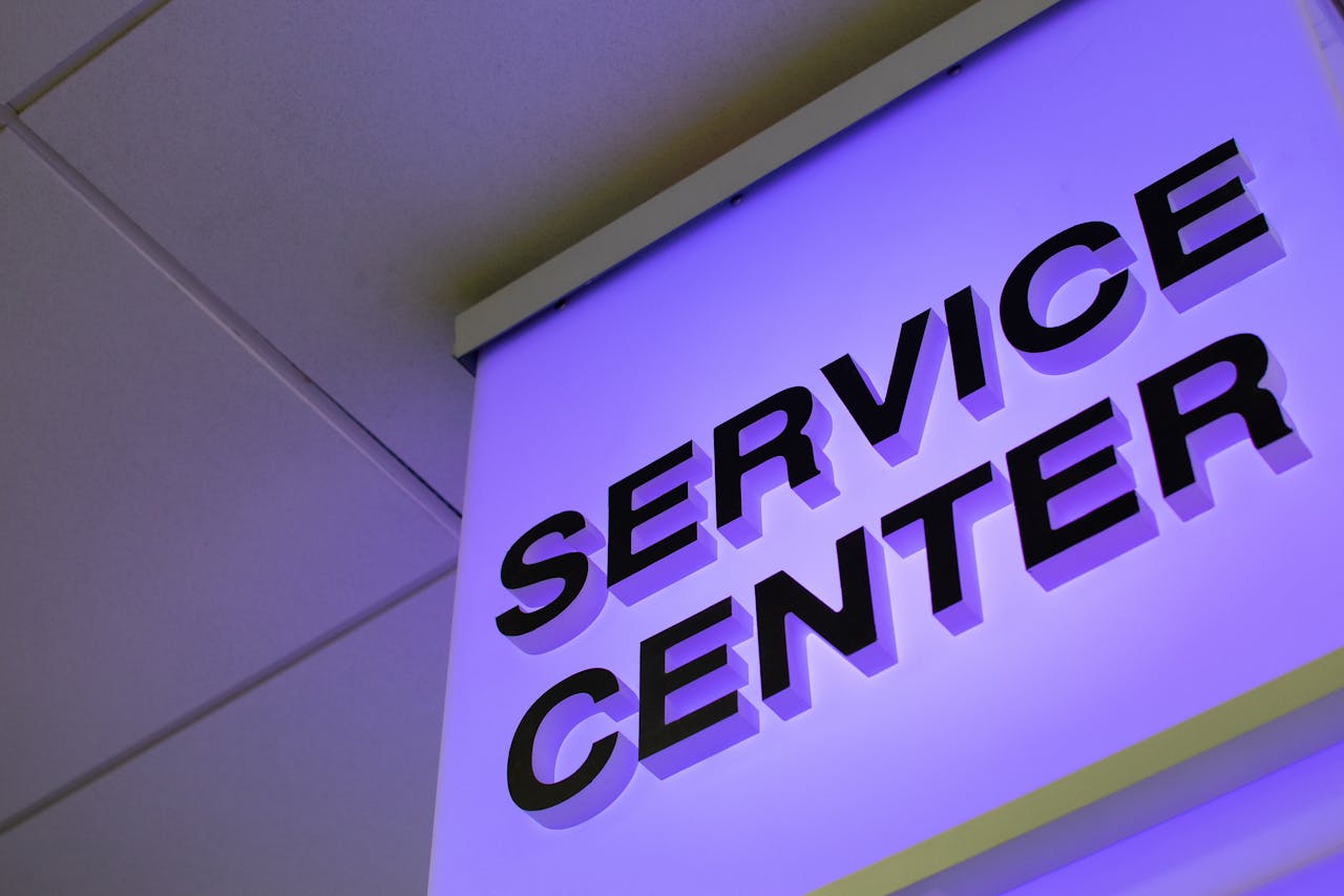 awards-img Close-up of a modern illuminated Service Center sign in a building interior.